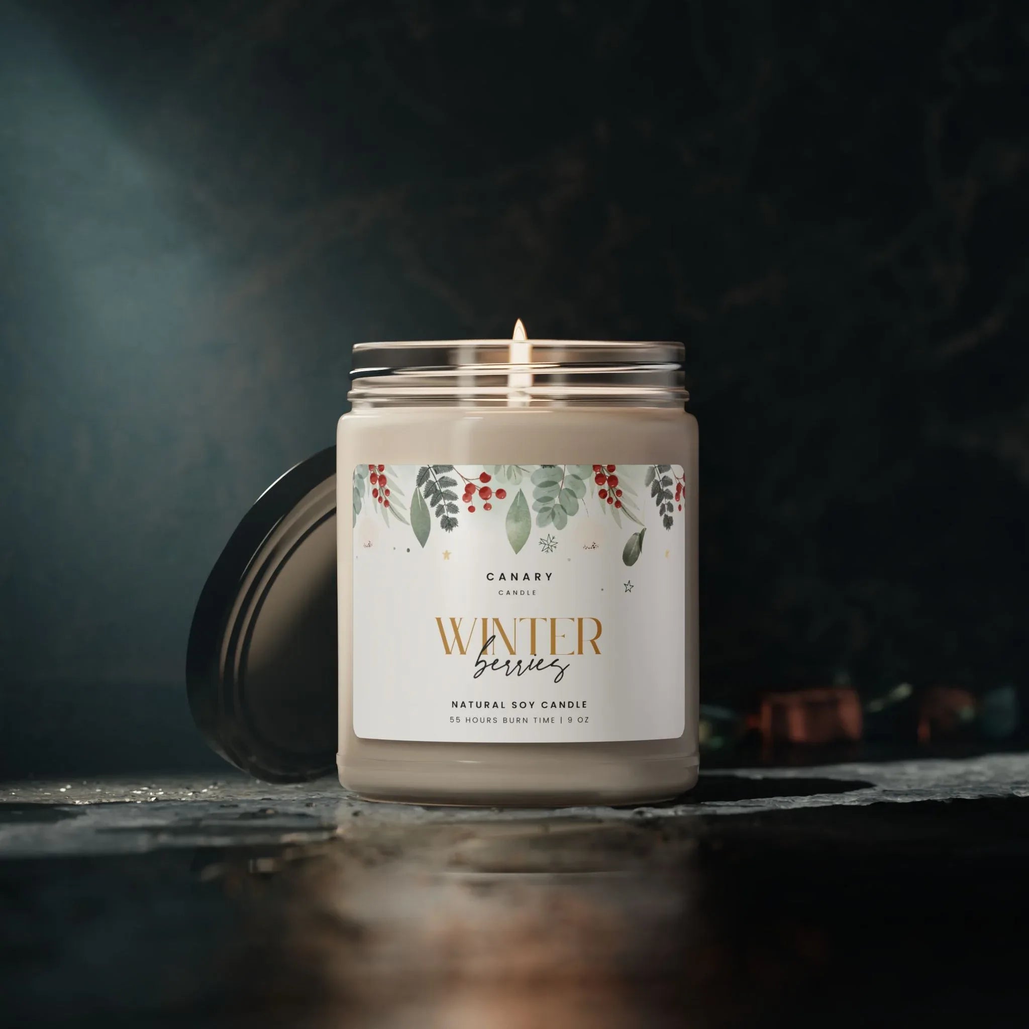 Winter berries scented candle in reusable glass jar with glossy label, glowing candlelight on dark background.
