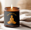 Funny soy candle in amber jar with 'Let that shit go' label and lit wick, creating a cozy ambiance.
