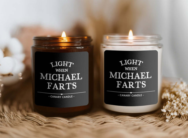 Funny personalized candle featuring humorous label 'Light When Michael Farts' in amber and clear jars.