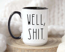 Sarcastic coffee mug with hand-lettered phrase 'Well, Shit.' in black on white ceramic with a colored handle.